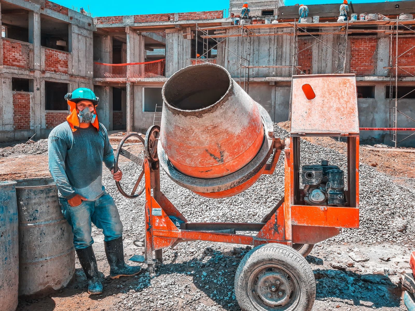 A construction worker beside a cement mixer on a building site