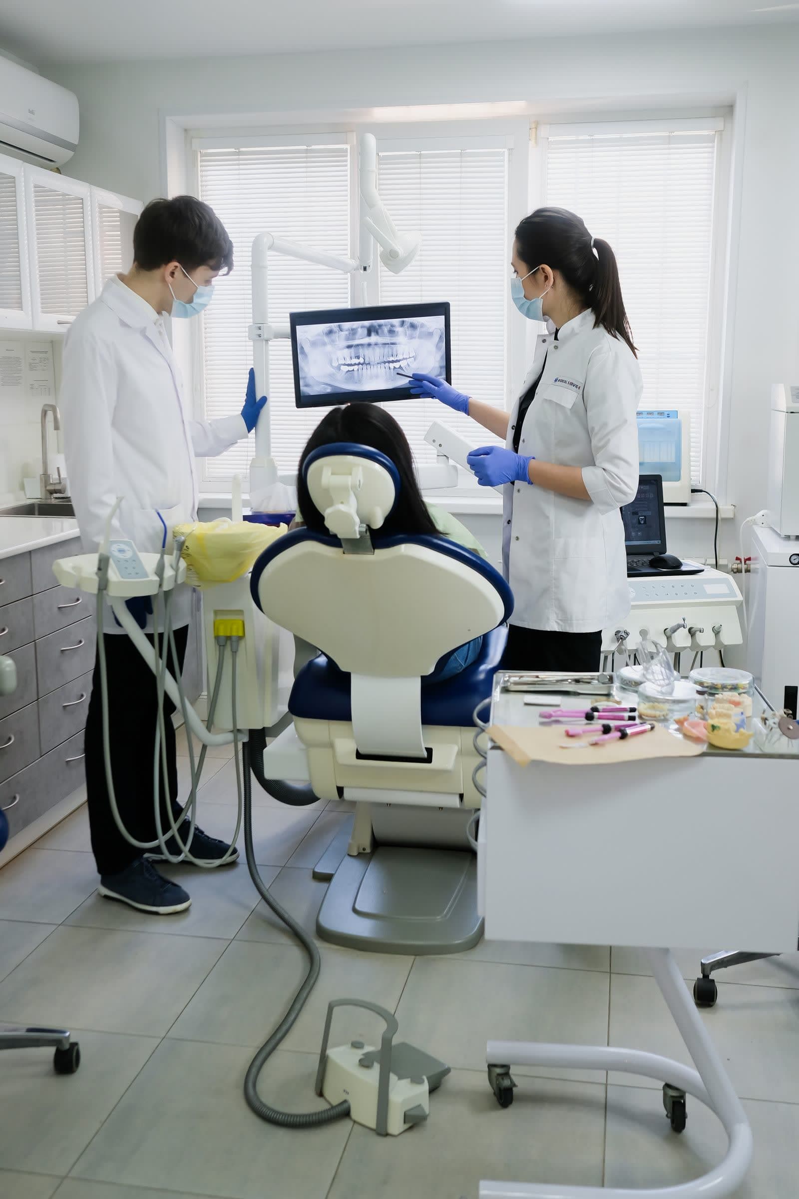 A dental treatment room with a chair, overhead light and instrument tray
