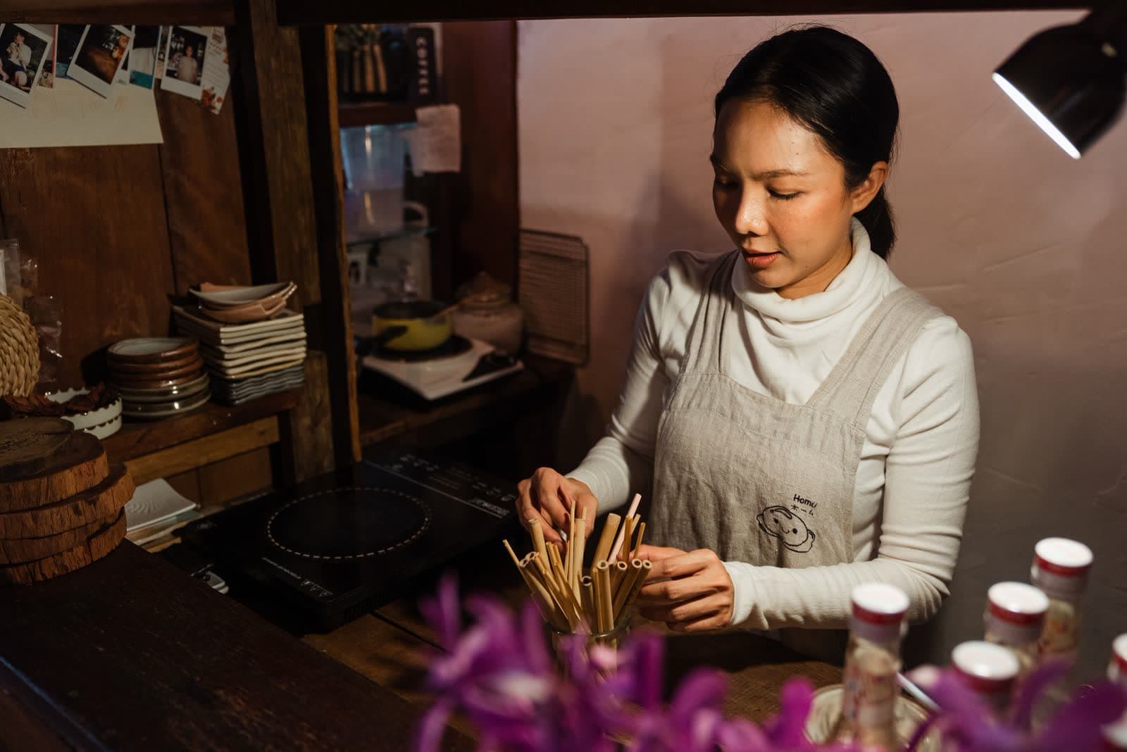 A shopkeeper arranging stock behind the counter of a small shop